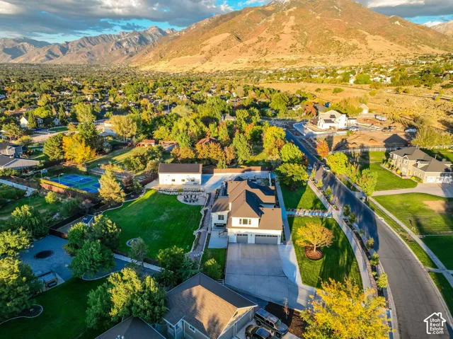Mountainous backdrop, expansive green spaces, paved roads, visible tennis court, and manicured landscaping