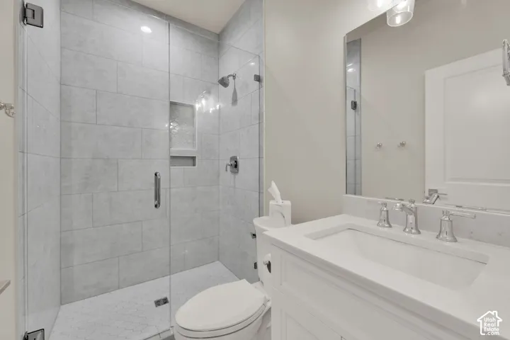 3/4 bathroom on main floor.Frameless glass shower enclosure with subway tile surround, integrated shower niche, white vanity with integrated sink, and polished chrome fixtures