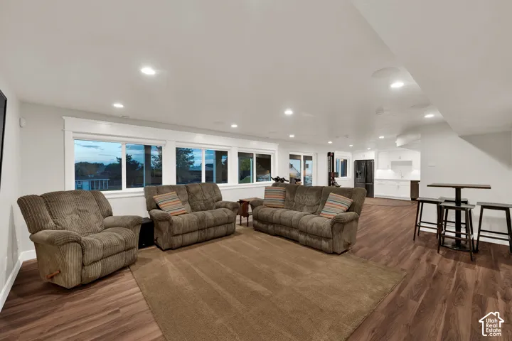 Recessed lighting, wood-finish flooring, white walls, multiple windows, and a built-in kitchen area