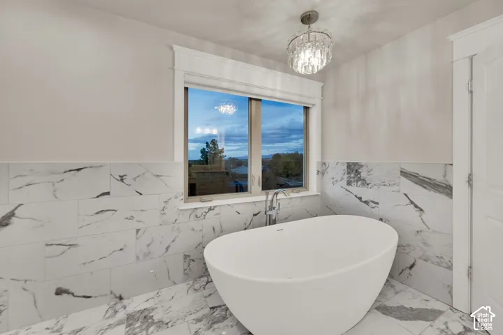 Primary Bathroom. Freestanding soaking tub with a floor-mounted faucet, complemented by large format wall and floor tiles