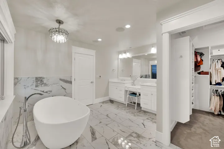 Primary BathroomFreestanding soaking tub with floor-mounted faucet, dual vanity with undermount sinks, and an integrated closet system with shelving