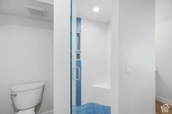 Pool Bathroom.  Walk-in shower with clear glass enclosure, blue penny tile accents, recessed lighting, and a built-in shower bench