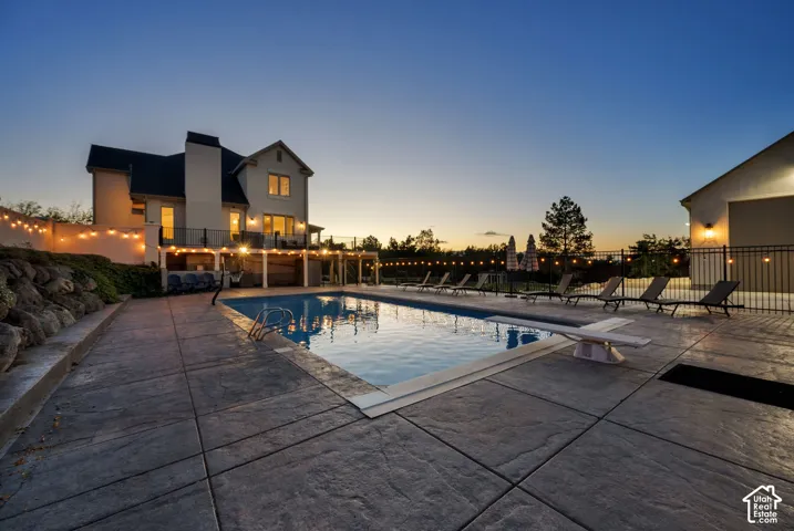 Rectangular in-ground swimming pool with diving board, surrounded by stamped concrete patio