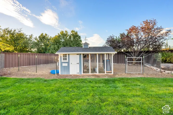 Chicken coop or dedicated animal enclosure featuring a painted wood-frame structure and a fenced run