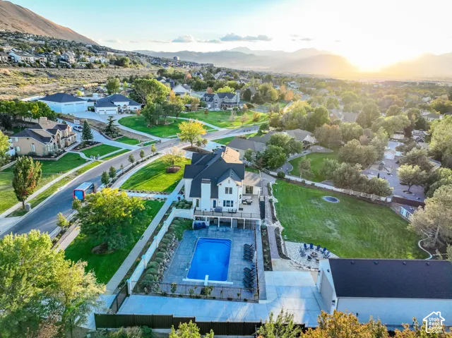White exterior with black roof, extensive landscaping, private swimming pool with surround, spacious wood-finish decking, and an expansive lawn area