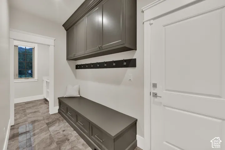 Entryway featuring tile flooring, built-in bench with storage, integrated upper cabinetry, and a white paneled door