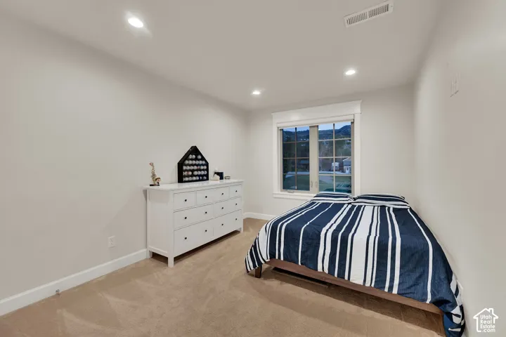 Recessed lighting illuminates neutral-toned walls and carpeted flooring