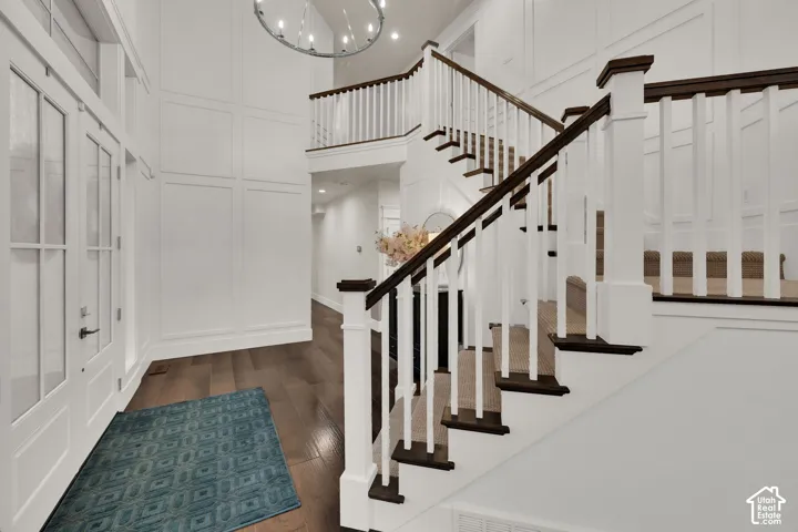 Two-story entry with wood-finish flooring, staircase featuring white risers and dark wood treads, and white paneled walls