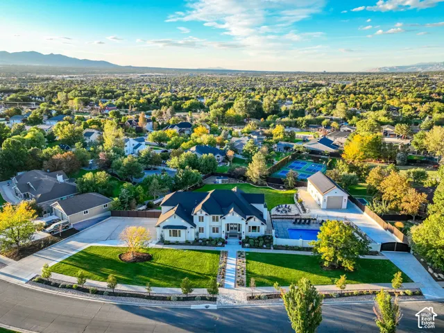Expansive lot featuring a main residence, detached garage, swimming pool with surrounding patio, tennis court, and manicured landscaping