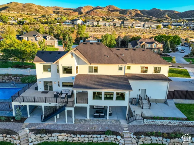 Expansive multi-level deck with a swimming pool, covered patio, and mountain backdrop