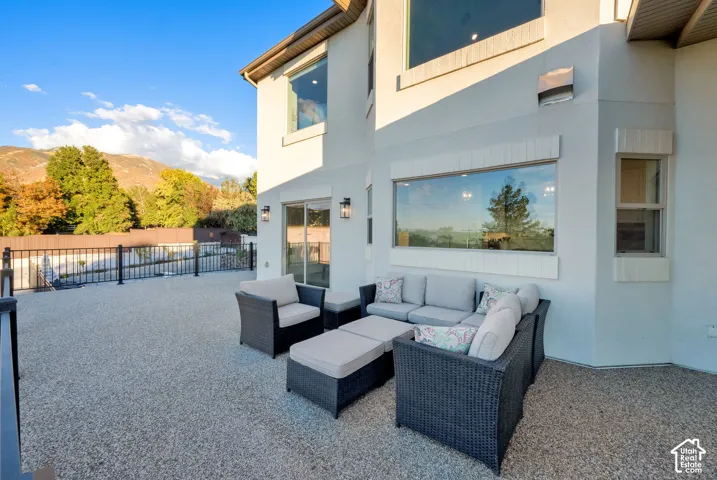 Expansive outdoor patio with a textured aggregate surface, black metal railing, sliding glass door, and large picture windows