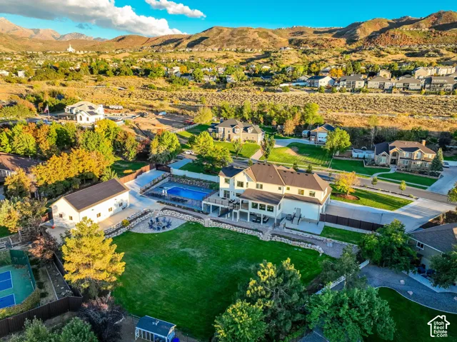 Expansive property featuring a large main residence with multiple decks, an outdoor swimming pool, a separate outbuilding, a manicured lawn, and a multi-sport court