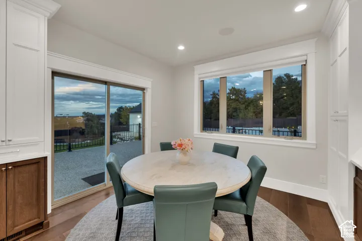 Recessed lighting, wood-finish flooring, built-in cabinetry with white and wood-finish panels, sliding glass door, and multi-pane window