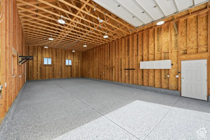 Expansive interior space featuring a light gray epoxy flooring, exposed wood framing, multiple windows, and a white interior door