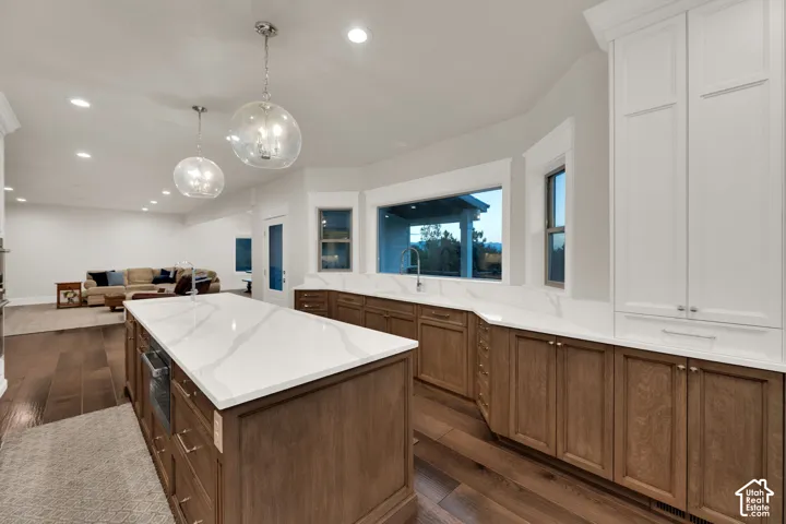 Spacious kitchen with a large central island, white countertops, and wood-finish flooring