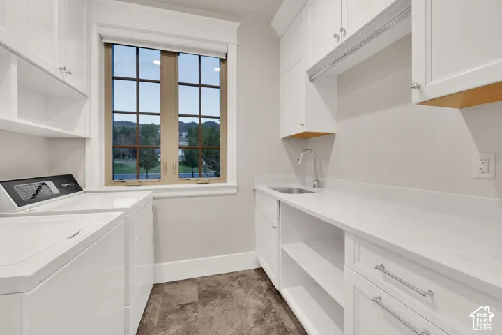 White cabinetry, spacious countertops, integrated stainless steel sink, large window with grid pattern, and durable tile flooring