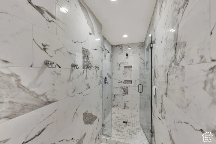 Primary Bathroom. Walk-in shower with full-height tile surround, recessed lighting, glass enclosure, and multiple shower fixtures