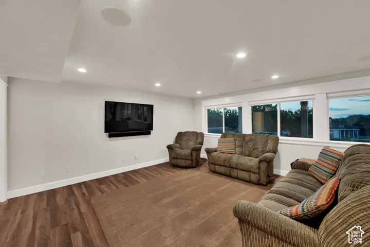 Recessed lighting, ceiling-mounted speakers, wood-finish flooring, built-in wall-mounted television, and a row of windows