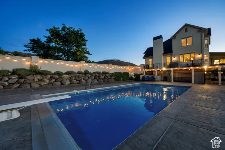 In-ground swimming pool with diving board, stamped concrete patio, stone retaining wall, and multi-level exterior decking
