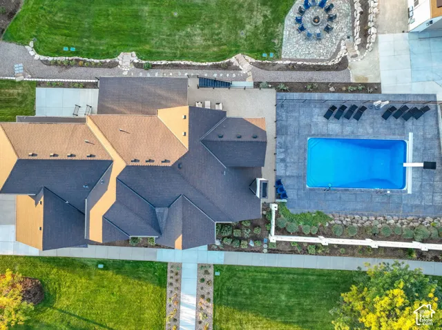 Landscaped grounds with a rectangular swimming pool, paver patio, and stone fire pit area