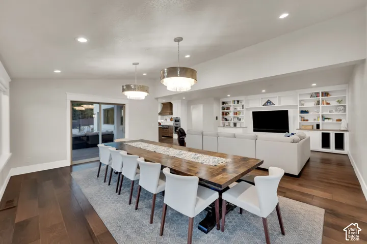 Hardwood flooring, recessed lighting, built-in shelving, two tiered chandeliers, and a sliding glass door