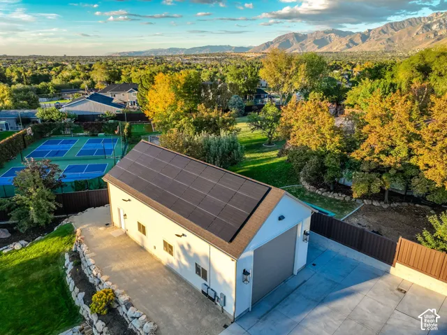 Detached structure featuring a multi-panel solar array, roll-up garage door, exterior wall sconces, and a paved driveway