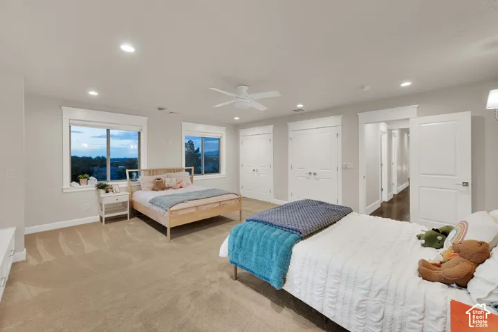Recessed lighting, ceiling fan, two windows with white trim, two sets of bi-fold closet doors, and an additional white door