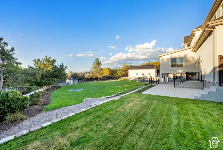 Expansive lawn area with a concrete patio, a gravel path, and a secondary structure