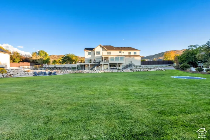 Expansive manicured lawn with a terraced retaining wall and multi-level rear exterior
