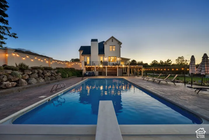 Expansive outdoor pool area featuring a diving board, surrounding stamped concrete patio, and a retaining wall with integrated plantings
