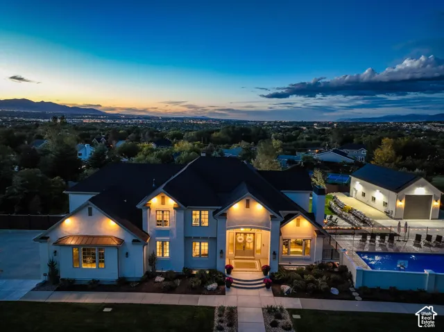 Expansive residence featuring a manicured lawn, an in-ground swimming pool, a separate auxiliary building, and extensive landscaping