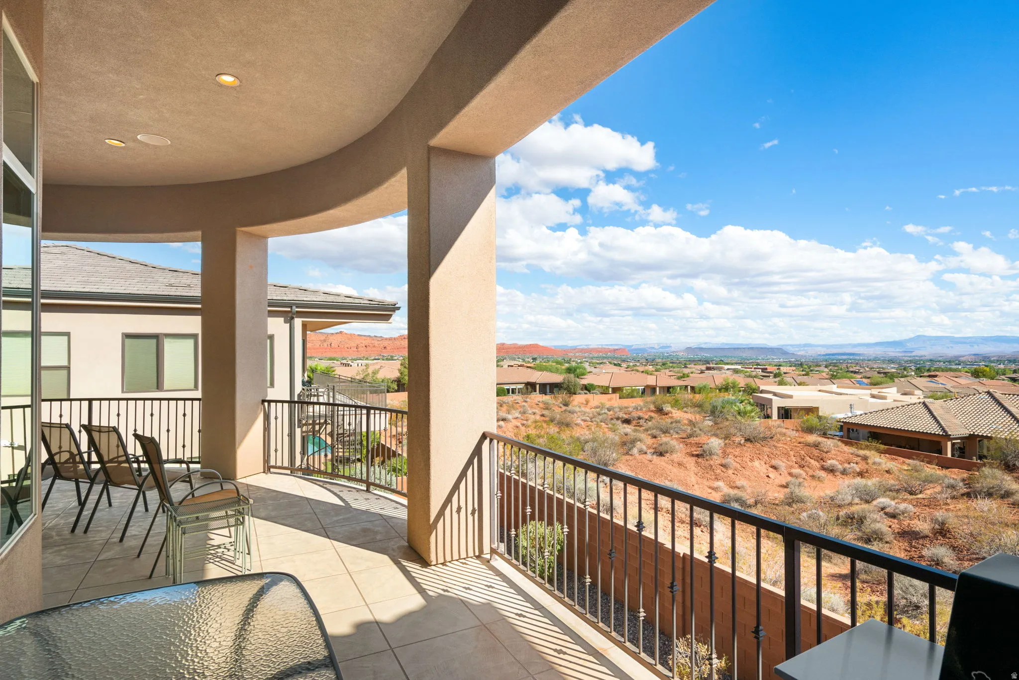 Curved balcony featuring stucco columns, tile flooring, built-in ceiling lighting, and a metal railing