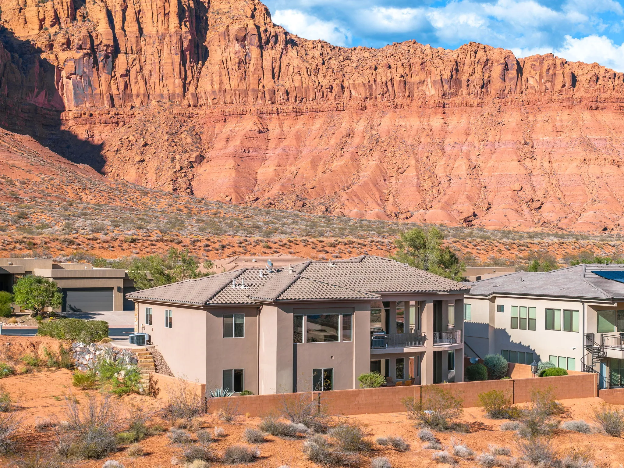 Contemporary stucco exterior with multiple balconies, tile roof, and desert landscaping