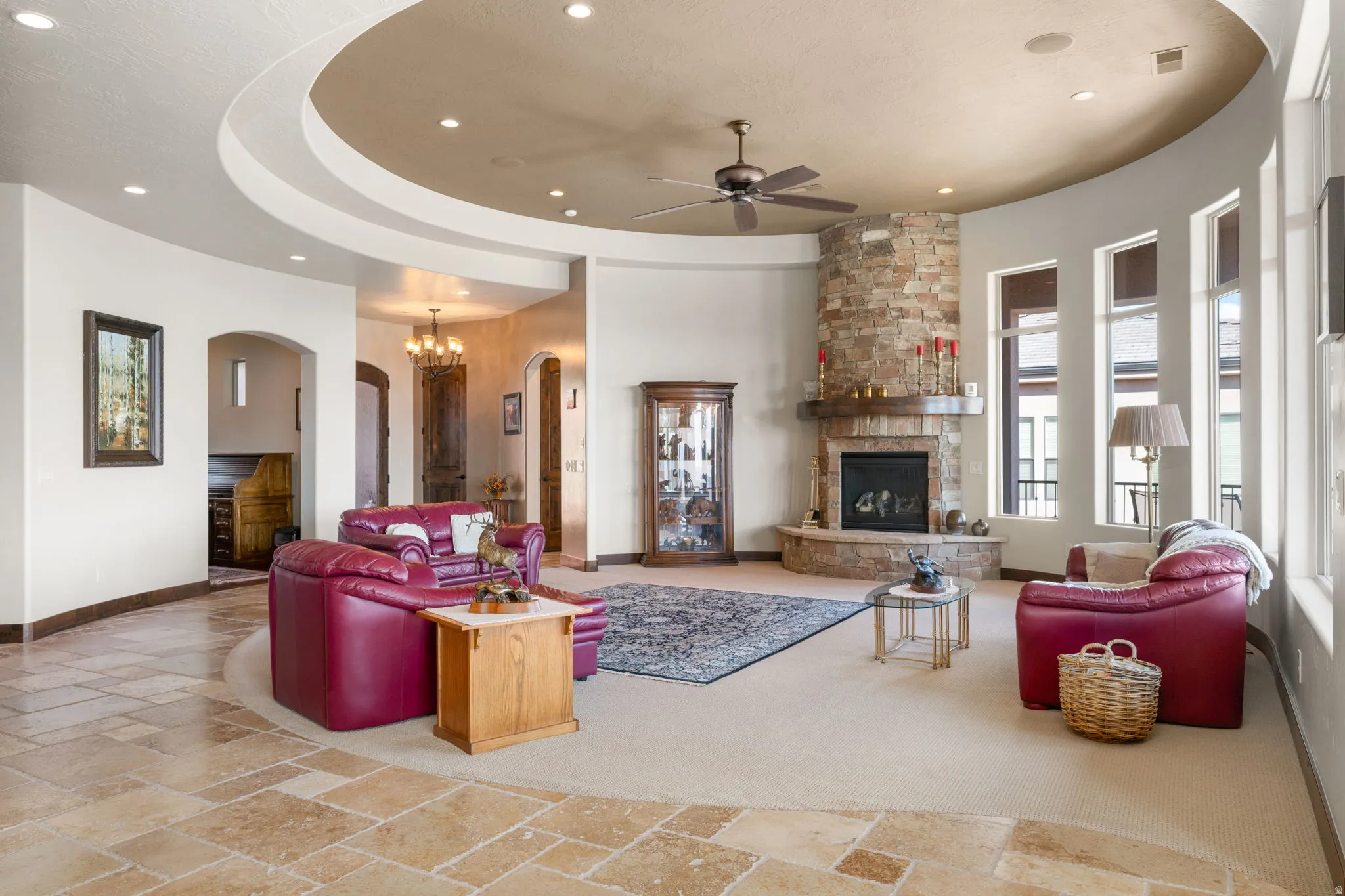 Curved architectural details, stone fireplace with hearth, multiple arched doorways, recessed lighting, and a ceiling fan