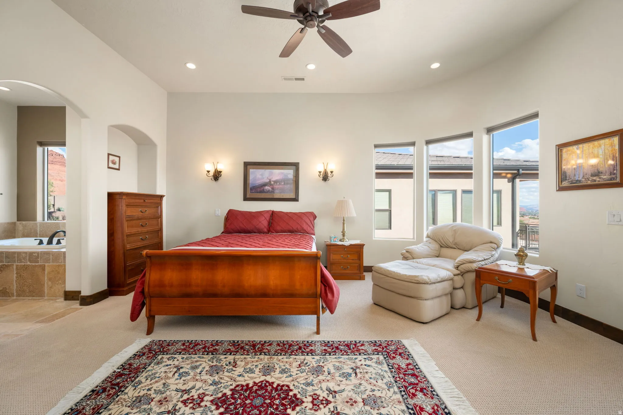 Primary Bedroom. Recessed lighting, ceiling fan, arched doorway, and built-in soaking tub with tile surround