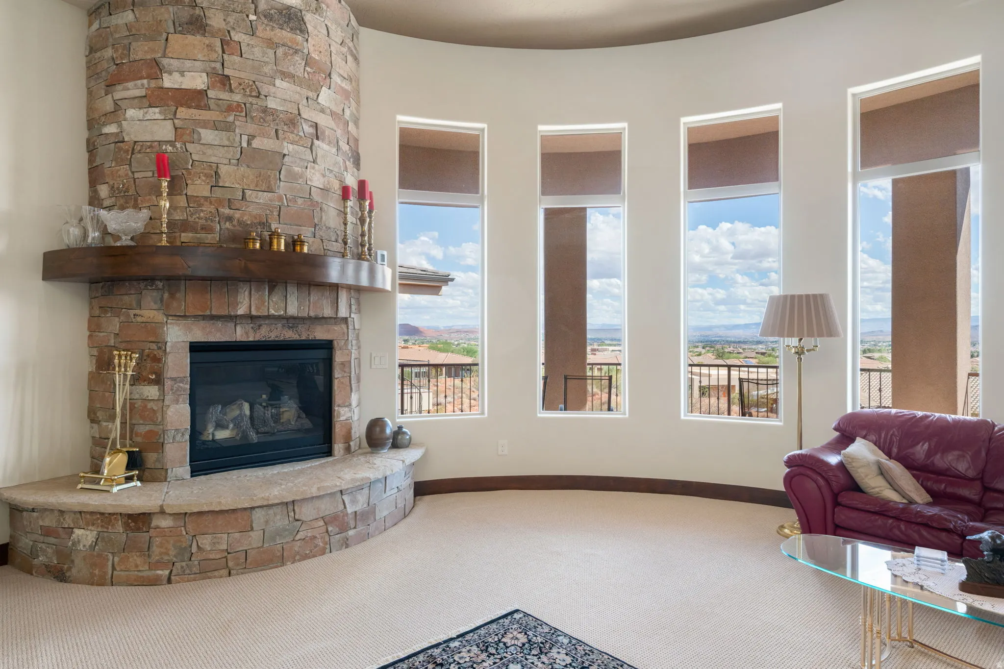 Curved architectural wall featuring multiple tall windows, a built-in stone fireplace, a stone hearth, and a wood mantel