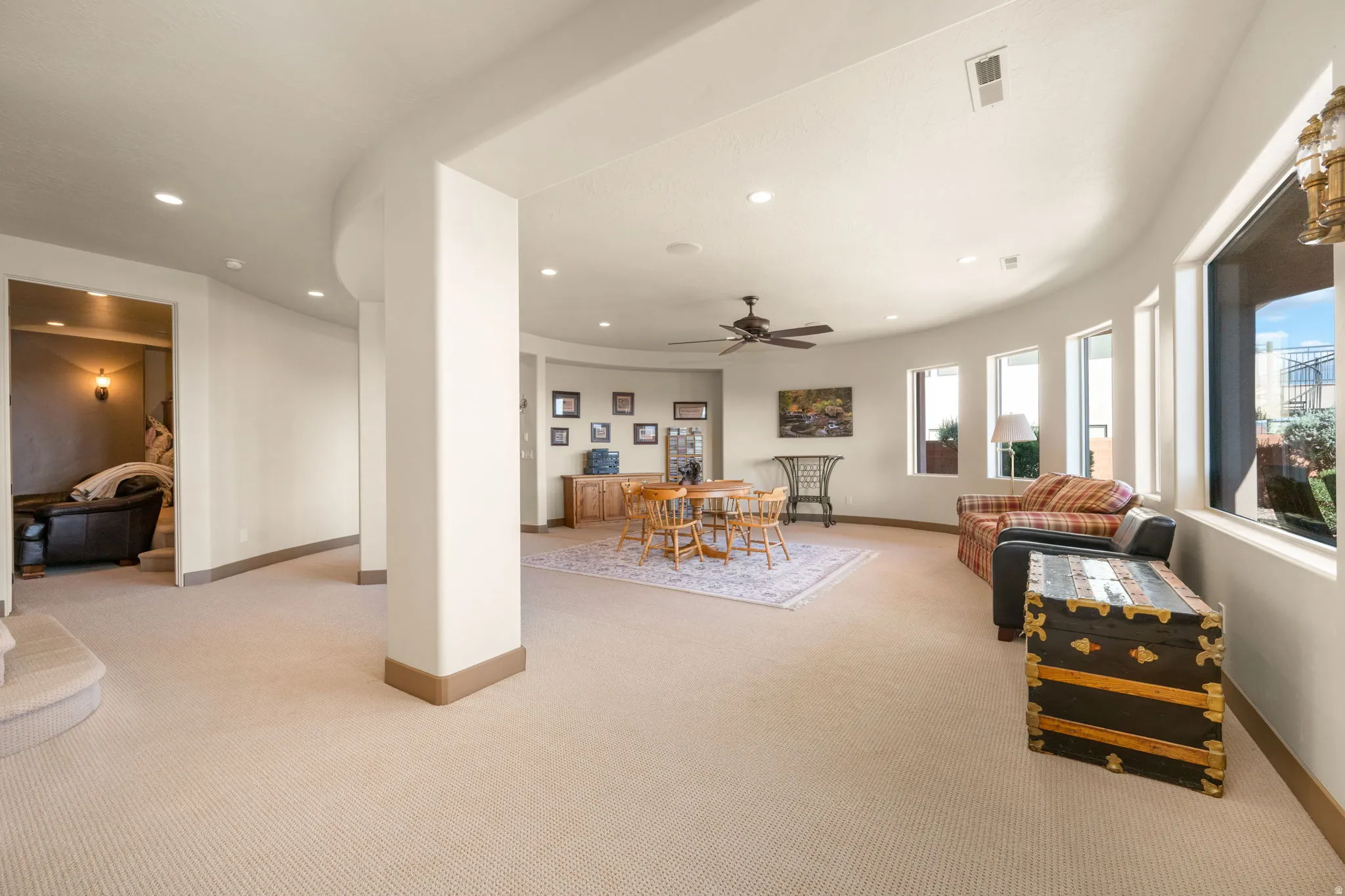 Curved architectural elements, recessed lighting, ceiling fan, multiple windows, and carpet flooring
