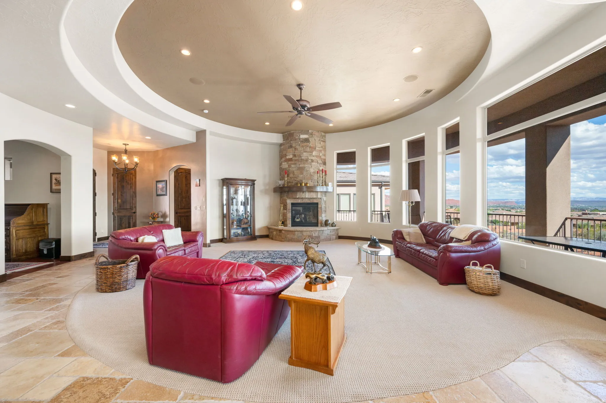 Expansive living space featuring a stone-clad fireplace, curved walls, recessed lighting, and large windows