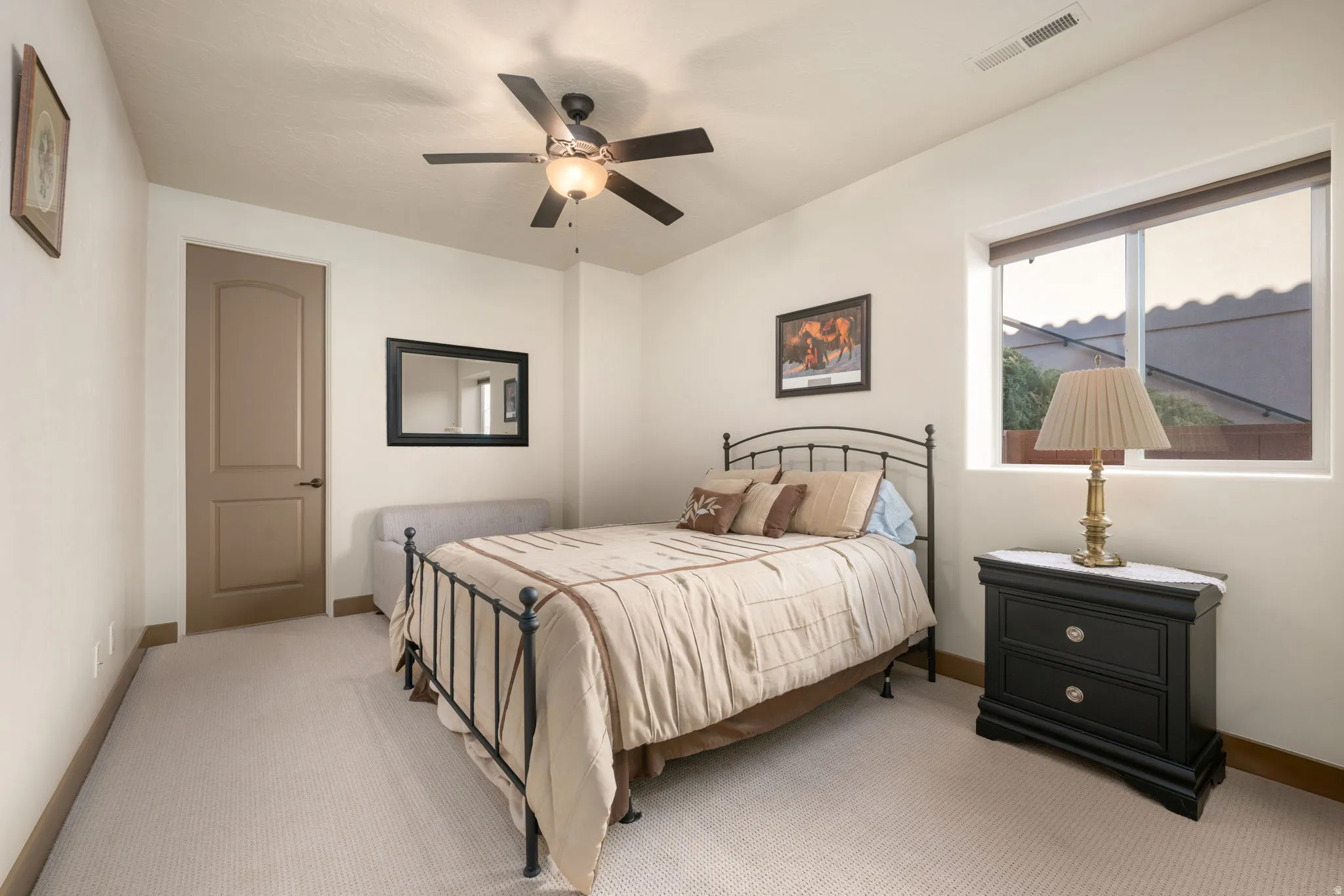 Room featuring carpet flooring, a window with roller shades, a ceiling fan with integrated lighting, and a solid-core interior door