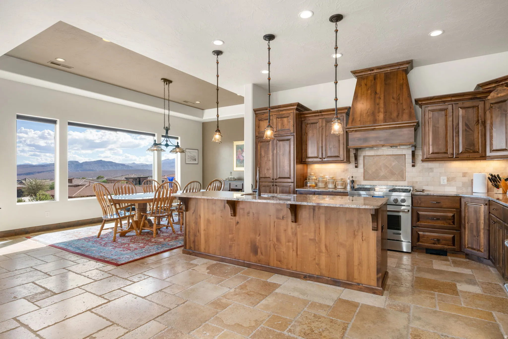 Gourmet kitchen featuring a wood island with pendant lighting, granite countertops, stainless steel appliances, and wood cabinetry