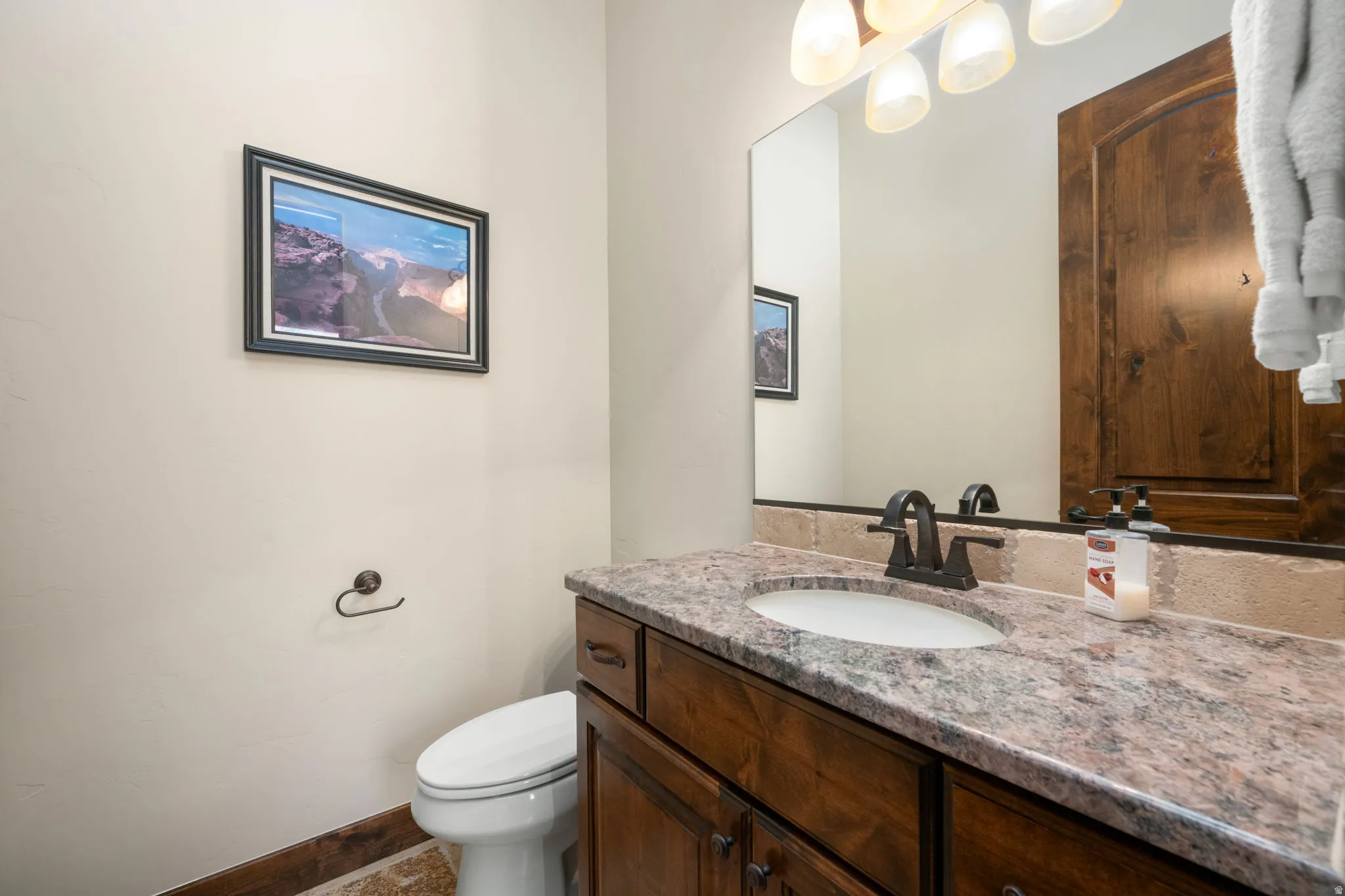 Vanity featuring a stone countertop, an undermount sink, and a dark bronze faucet