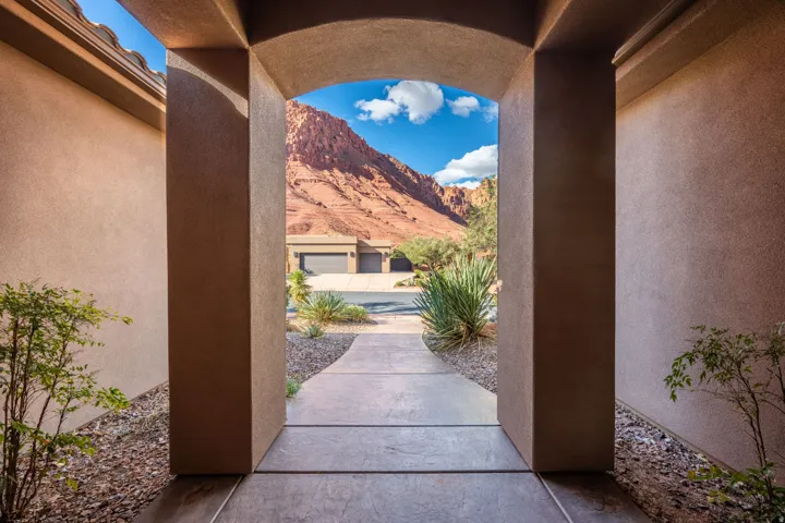 Archway entrance with a paved walkway, surrounded by low-maintenance landscaping and framed by a prominent mountain backdrop