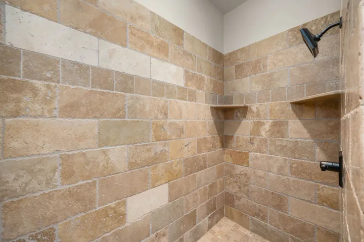Tiled shower with integrated shelving, matte black shower head, and coordinating floor tile