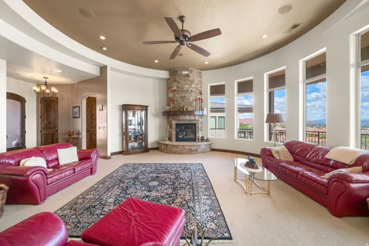 Stone fireplace with a wood mantel, floor-to-ceiling windows, and recessed lighting