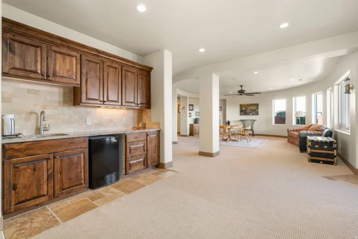 Built-in wet bar with wood cabinetry, integrated sink, and a mini-refrigerator