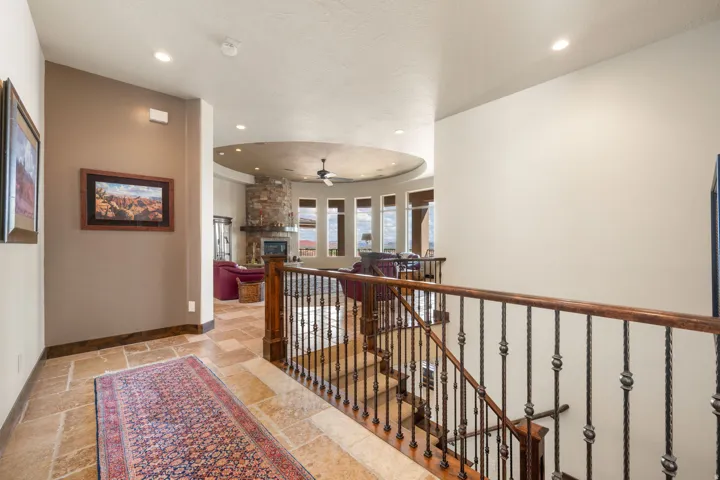 Stone tile flooring leading to a staircase with wood handrails and wrought iron balusters