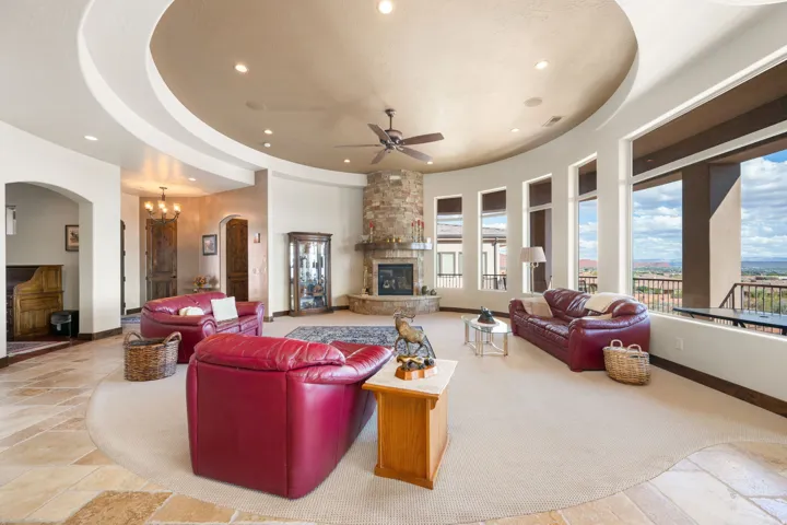 Expansive living space featuring a stone-clad fireplace, curved walls, recessed lighting, and large windows