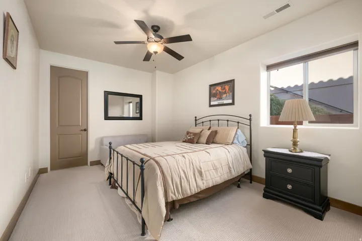 Room featuring carpet flooring, a window with roller shades, a ceiling fan with integrated lighting, and a solid-core interior door