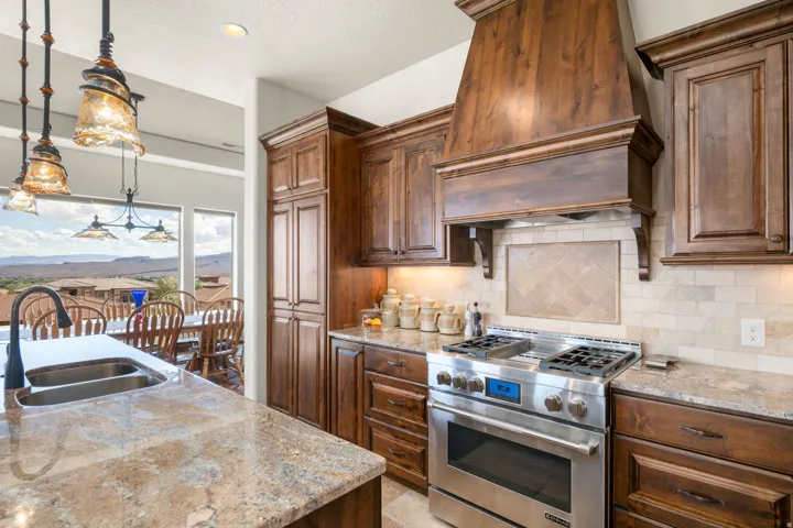Gourmet kitchen with wood cabinetry, stainless steel range, and stone countertops