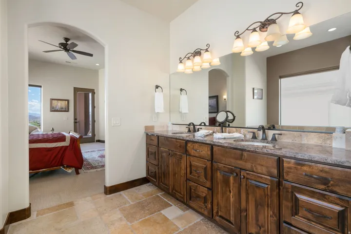 Dual vanity with dark wood cabinetry, stone countertops, and bronze-finish fixtures